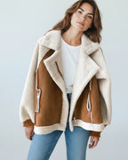 Frau trägt einen Schaffellmantel vor hellgrauem Hintergrund