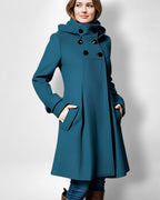 Frau trägt einen petrolblauen Jacke vor weißem Hintergrund