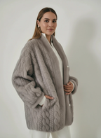 Frau trägt eine graue Strickjacke mit Zopfmuster und Perlenknöpfen