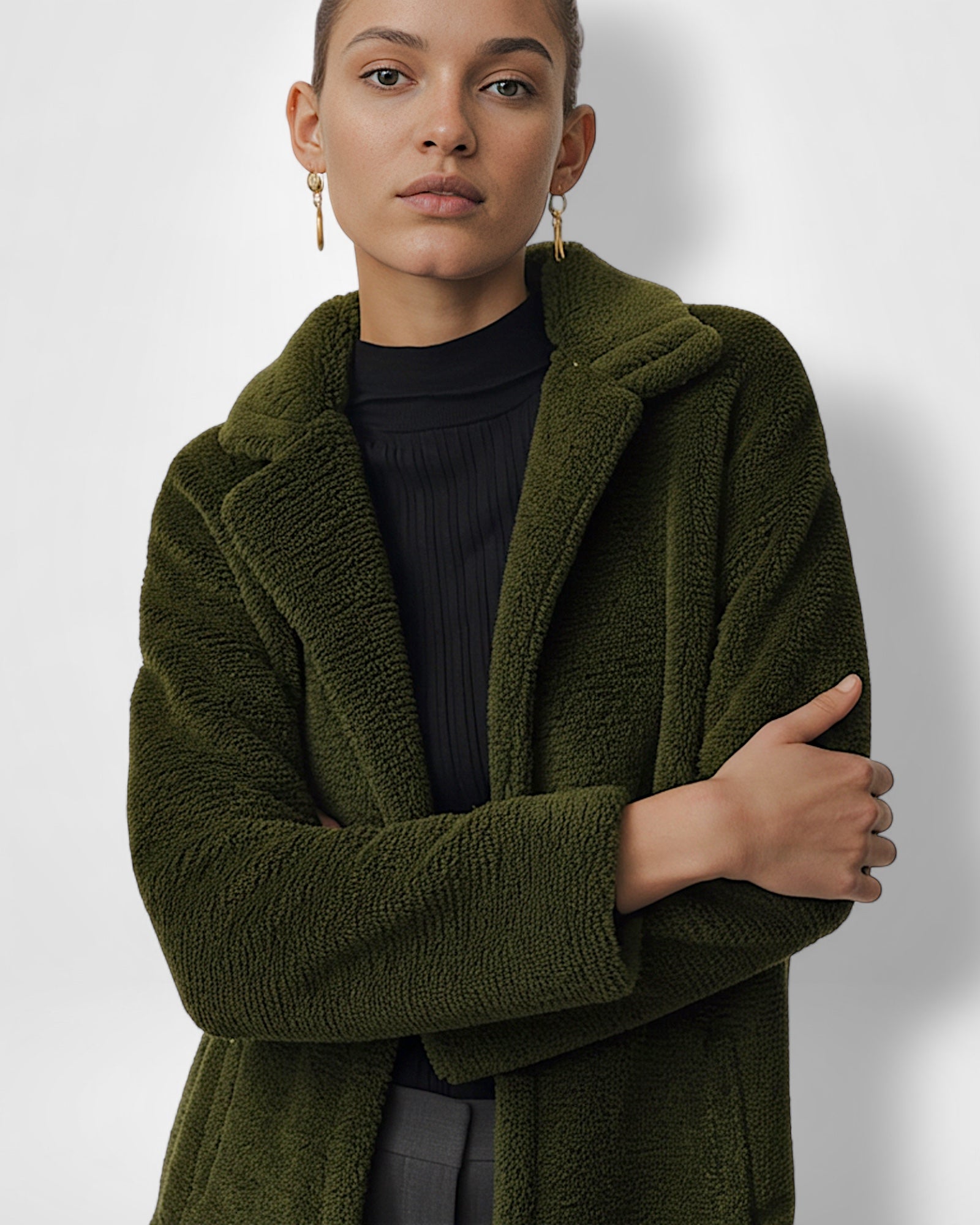 Frau trägt einen grünen Mantel vor weißem Hintergrund