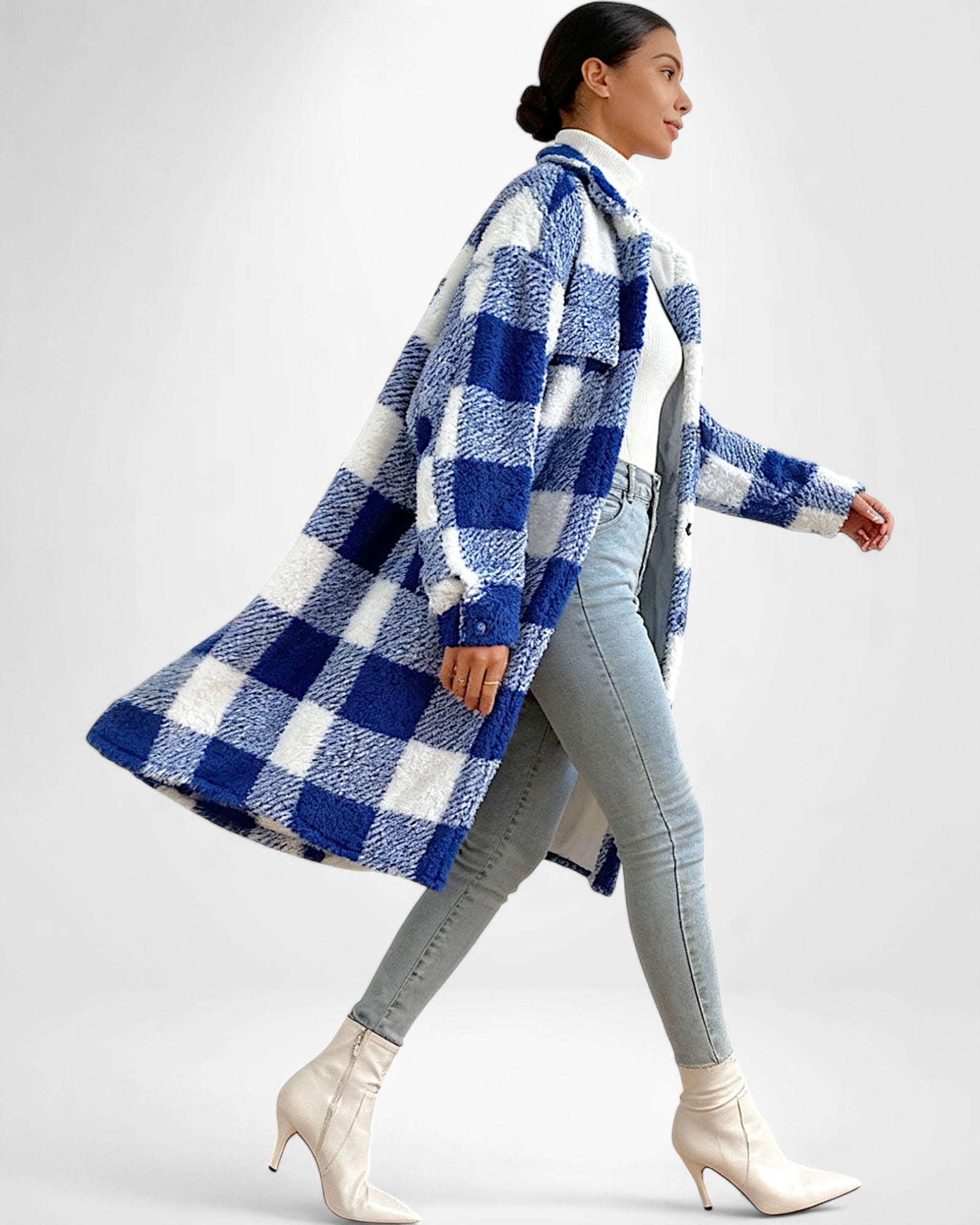 Frau trägt einen blau-weiß karierten Teddy-Mantel vor weißem Hintergrund