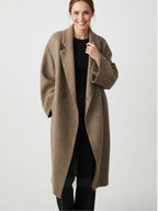 Frau trägt einen braunen Mantel vor weißem Hintergrund