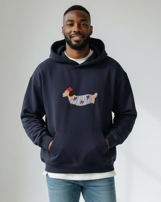 Junger Mann trägt einen marineblauen Hoodie mit Dackelmotiv vor schlichtem Hintergrund