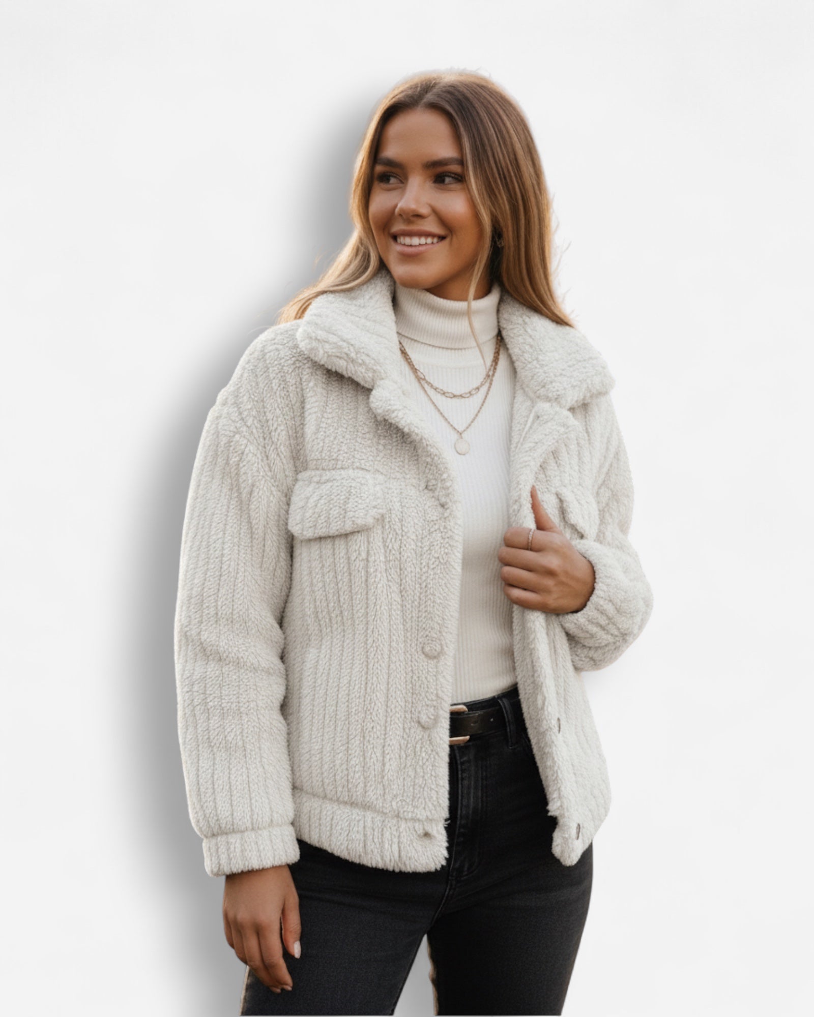 Frau trägt eine weiße Sherpa-Jacke vor hellgrauem Hintergrund