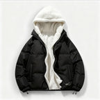 Schwarze Steppjacke mit Kapuze und weißem Fleecefutter vor hellgrauem Hintergrund.