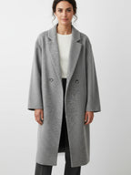 Frau trägt einen grauen Mantel vor weißem Hintergrund