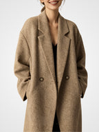 Person trägt einen braunen Mantel vor weißem Hintergrund