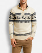 Mann trägt einen cremefarbenen Pullover mit Rentiermuster vor hellgrauem Hintergrund