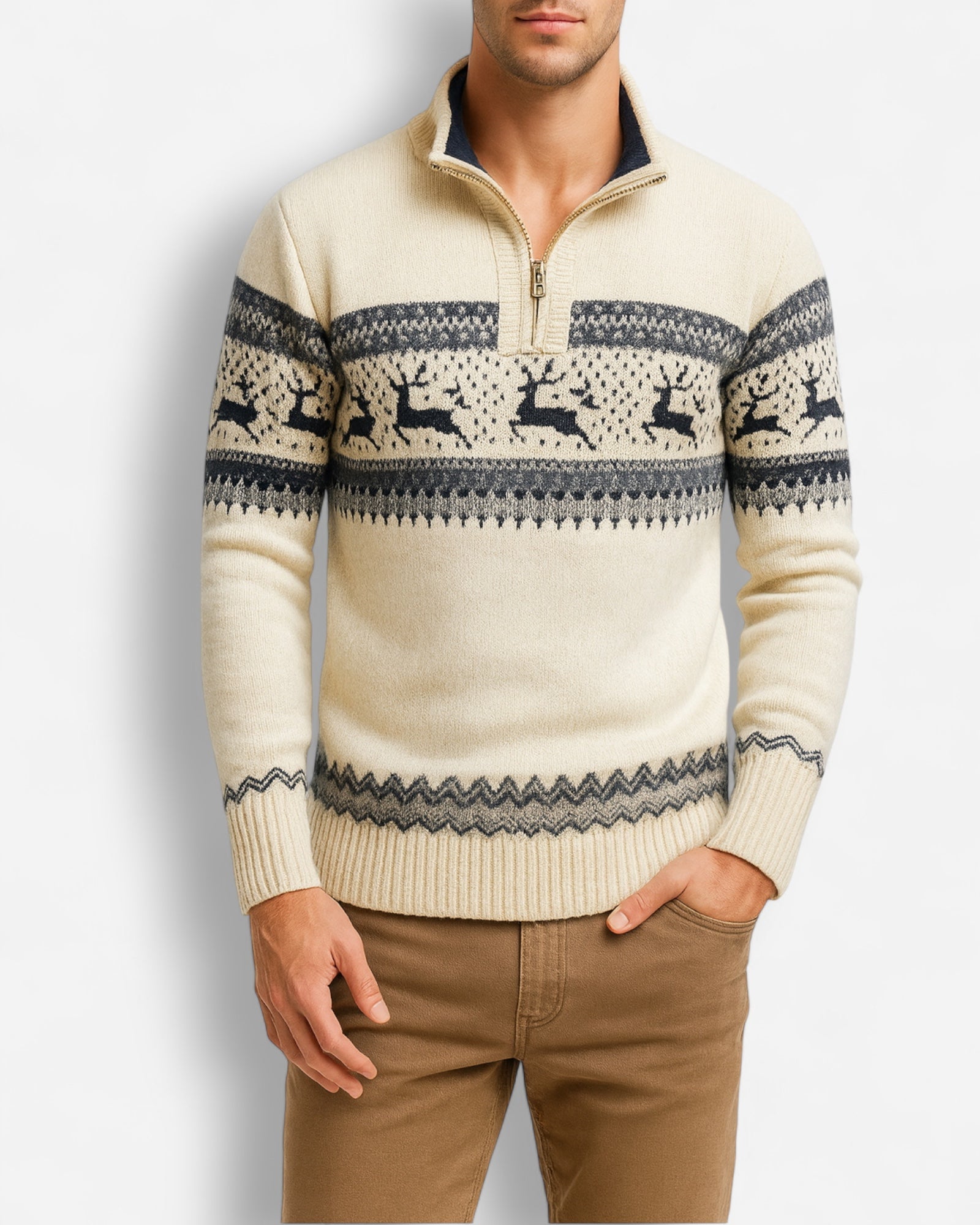Mann trägt einen cremefarbenen Pullover mit Rentiermuster vor hellgrauem Hintergrund