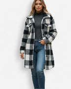 Frau trägt einen schwarz-weiß karierten Teddy-Mantel in Hemdjacken-Optik vor weißem Hintergrund