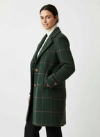 Frau trägt einen grünen karierten Mantel vor weißem Hintergrund 0