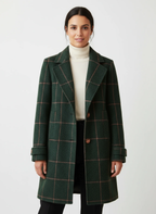 Frau trägt einen grünen karierten Mantel vor weißem Hintergrund 1