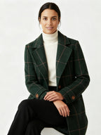 Frau trägt einen grünen karierten Mantel vor weißem Hintergrund 2