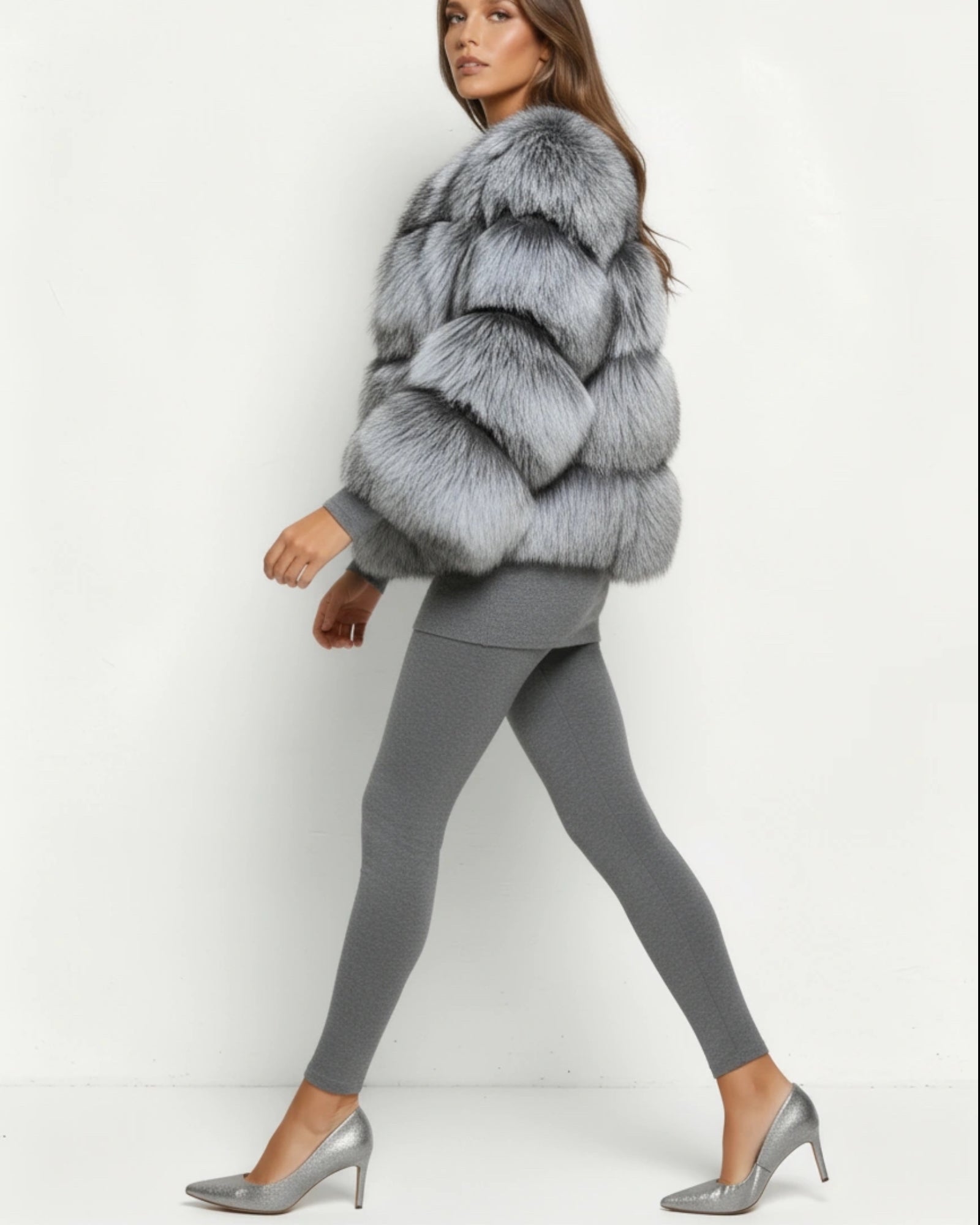 Frau in grauer flauschiger Kurzjacke und grauem Outfit vor weißem Hintergrund