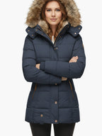 Frau trägt eine marineblaue Steppjacke mit fellgefütterter Kapuze vor weißem Hintergrund