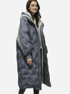 Frau trägt einen langen blauen Puffermantel mit Kapuze vor weißem Hintergrund