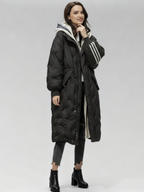 Frau trägt einen langen schwarzen Puffermantel vor weißem Hintergrund