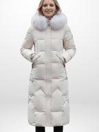 Frau trägt einen langen weißen Puffermantel mit Kapuze mit Kunstfellbesatz vor weißem Hintergrund