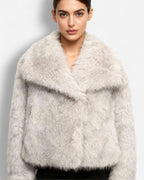 Frau trägt eine ecrufarbene flauschige Jacke vor einfarbigem Hintergrund