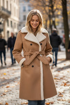 Frau trägt einen beigen Wintermantel mit weißem Teddykragen auf einer Stadtstraße im Herbst
