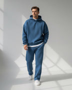 Ein Mann trägt ein blaues Oversized-Loungewear-Set mit Kapuzen-Sweatshirt und Jogginghose 0