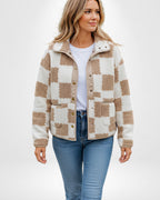 Frau trägt eine beige-weiß karierte Sherpa-Fleecejacke
