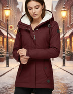 Frau trägt eine warme Winterjacke mit Kapuze und weichem Futter in Burgunder in winterlicher Stadtumgebung bei gemütlicher Atmosphäre