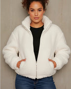 Frau trägt eine weiße Teddyjacke vor einfarbigem Hintergrund