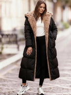 Frau trägt einen langen schwarzen Steppmantel mit Kapuze mit Kunstfellfutter auf einer Straße