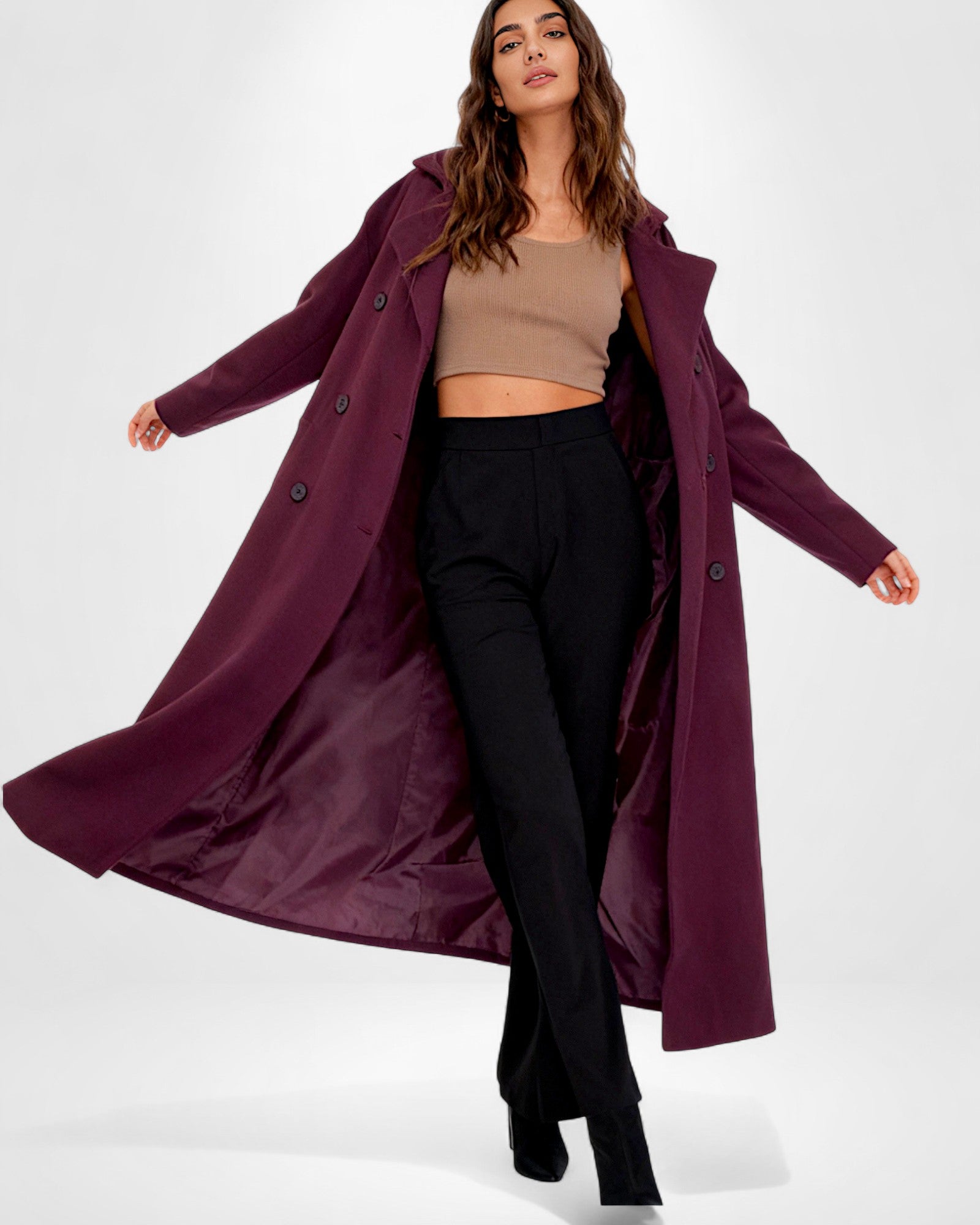 Frau trägt einen langen, zweireihigen Mantel vor weißem Hintergrund