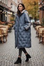 Frau trägt einen langen blauen Puffermantel mit Kapuze auf der Straße