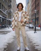 Frau trägt eine Fleecejacke mit Stehkragen und beige Hose auf einer verschneiten Stadtstraße