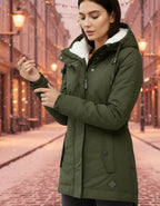 Frau trägt eine warme Winterjacke mit Kapuze und weichem Futter in Olivegrün in winterlicher Stadtumgebung bei gemütlicher Atmosphäre