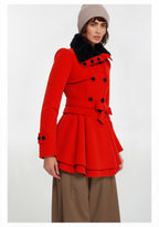 Frau trägt einen roten Mantel mit schwarzen Knöpfen und gefüttertem Kragen vor weißem Hintergrund