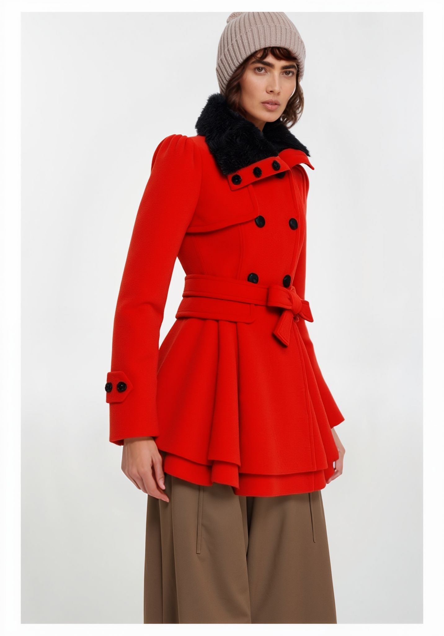 Frau trägt einen roten Mantel mit schwarzen Knöpfen und gefüttertem Kragen vor weißem Hintergrund