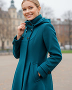 Frau trägt einen petrolblauen Wintermantel im Freien vor unscharfem Hintergrund