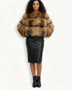 Frau in einem Kunst-Pelzmantel und schwarzem Lederrock vor weißem Hintergrund