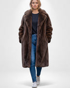 Frau trägt einen offenen braunen Maxi-Webpelzmantel vor weißem Hintergrund