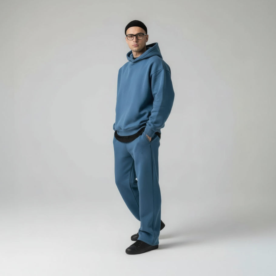 Ein Mann trägt ein blaues Oversized-Loungewear-Set mit Kapuzen-Sweatshirt und Jogginghose