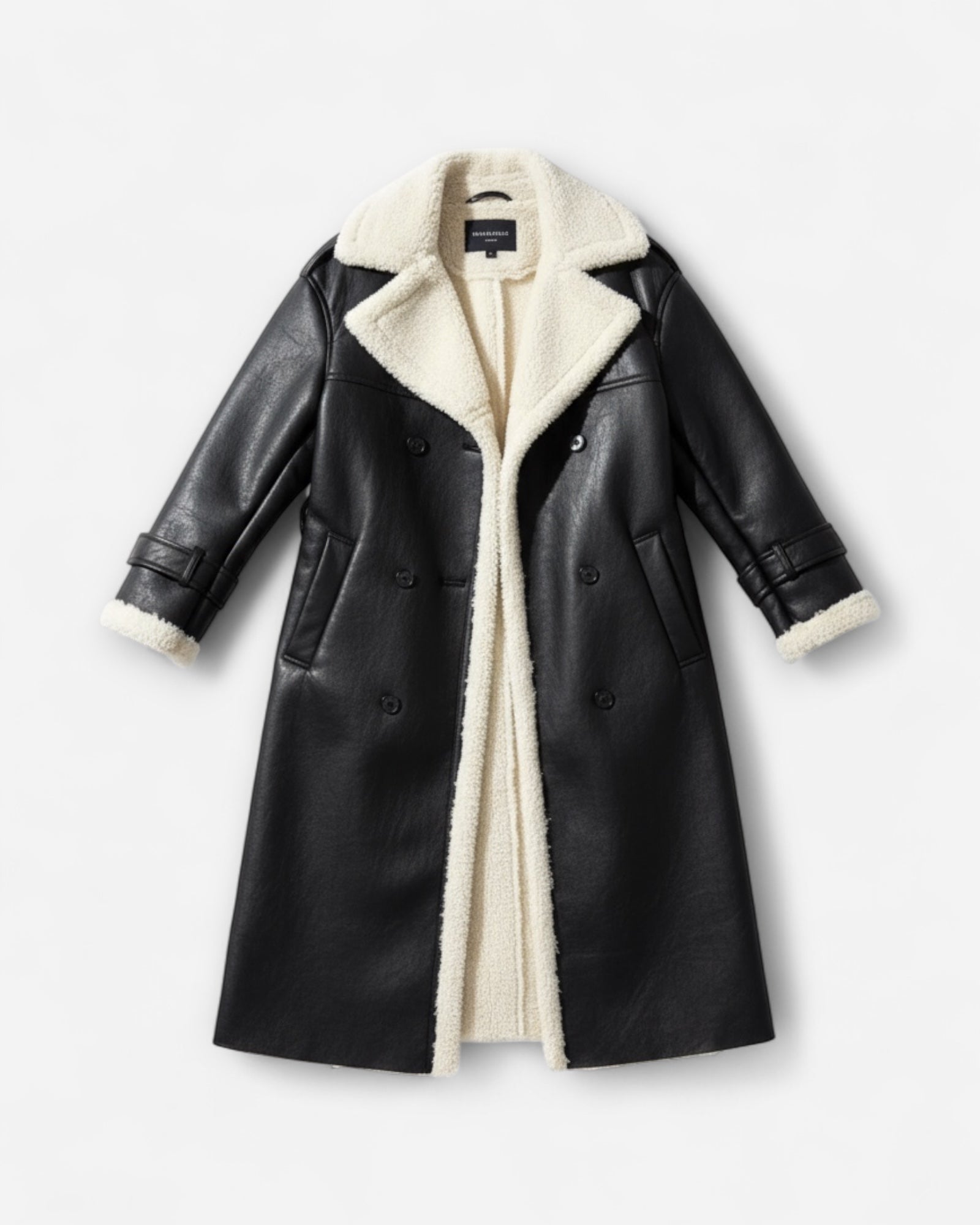 Schwarzer Mantel aus Kunstleder mit weißem Teddyfutter vor hellgrauem Hintergrund