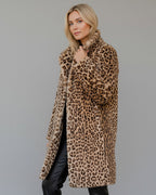 Frau trägt einen Mantel mit Leopardenmuster vor grauem Hintergrund