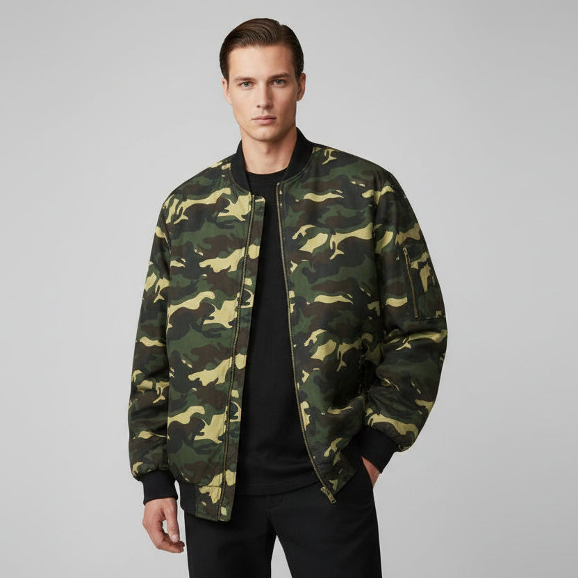 Ein Mann trägt eine Camouflage-Jacke vor grauem Hintergrund.